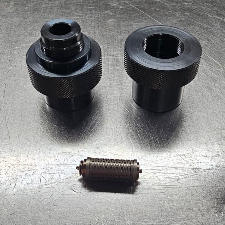 Three black mechanical components on a metallic surface