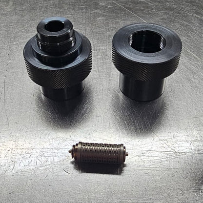Three black mechanical components on a metallic surface